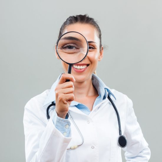 Portrait of beautiful female doctor looking through loupe.